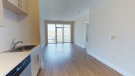 Unit 611 is a thoughtfully designed 1-bedroom, 1-bathroom residence that combines modern finishes with a bright, open layout. The living area is anchored by smooth hardwood-style flooring that extends throughout, reflecting natural light and contributing to the home's clean, contemporary aesthetic. Tall ceilings enhance the sense of openness and airiness throughout the main living space.

Floor-to-ceiling sliding glass doors lead to a private balcony, flooding the interior with abundant natural light and offering pleasant outdoor views. This seamless indoor-outdoor connection makes the living area feel expansive and inviting.

The kitchen is positioned adjacent to the main living space, featuring light cabinetry with modern hardware and integrated appliances, offering a functional and stylish workspace. The open-concept flow between the kitchen and living area makes the layout ideal for everyday living and entertaining.

The bedroom is accessible via a dedicated hallway, providing privacy and separation from the main living areas. Clean white walls throughout the unit create a neutral, versatile backdrop ready for personalization. The overall ambiance of Unit 611 is bright, modern, and welcoming, with quality finishes that reflect contemporary residential design standards.