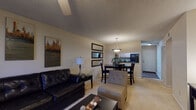 This single-floor model residence in Jacksonville, FL offers a thoughtfully designed layout that balances comfort and functionality. The open-concept living area features plush carpeting, a ceiling fan, and a textured ceiling, creating a relaxed and inviting atmosphere. Wall art and decorative mirrors add visual depth, while the space flows naturally into a dedicated dining area illuminated by a stylish pendant light fixture. A pass-through window connects the dining space to the kitchen, enhancing the sense of openness.

The kitchen is well-equipped with light wood cabinetry, dark countertops, black appliances including a range, dishwasher, and refrigerator, and durable hard-surface flooring. Ample cabinet storage extends to the upper walls, maximizing utility.

The bedroom is a serene retreat highlighted by an accent wall in a warm green tone, carpet flooring, a ceiling fan, and a window with drape panels that allow natural light. A built-in closet provides practical storage.

The bathroom features light wood cabinetry, a dark countertop vanity, and well-lit mirrors, maintaining the cohesive design language found throughout the home. A dedicated in-unit laundry area with a full-size washer and dryer adds everyday convenience. Overall, the residence presents a clean, modern aesthetic suited for comfortable living.