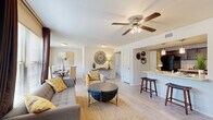 Located at 815 S Donaghey Ave in Conway, Arkansas, this single-story, 2-bedroom, 2-bathroom residence offers a thoughtfully designed layout that maximizes comfort and functionality. The open-concept living, dining, and kitchen area forms the heart of the home, bathed in natural light from large windows dressed with floor-length curtains. Light wood-style flooring runs throughout the main living areas, complemented by ceiling fans in the living room and bedrooms. The kitchen features rich dark cabinetry, light countertops, a black refrigerator, and a breakfast bar with pendant lighting — ideal for casual dining. The adjacent dining area accommodates a full table and benefits from a window overlooking the outdoors. Both bedrooms are carpeted and generously sized, each equipped with a ceiling fan and a dedicated walk-in closet with built-in shelving. The primary bedroom offers a comfortable, private retreat. The two bathrooms are finished with dark wood vanities, light countertops, and wood-style flooring. A connecting hallway provides access to all rooms and includes a utility panel area. The overall aesthetic is clean, neutral, and inviting, with a layout that balances open communal spaces with private quarters.
