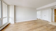 Located at 221 Balliol St in Toronto's sought-after Davisville Village neighbourhood, this well-appointed one-bedroom, one-bathroom unit offers a thoughtfully designed layout with a clean, modern aesthetic throughout. Light wood flooring flows seamlessly across the living areas and bedroom, complementing the neutral palette of soft white and warm grey tones that define the interior.

The spacious living room is a standout feature, anchored by a large wall of floor-to-ceiling windows that flood the space with natural light and frame impressive views of the Toronto skyline. These windows open to a private balcony, extending the living space outdoors. The kitchen is efficiently laid out with glossy white upper cabinetry, sleek grey lower drawers, stainless steel appliances including a range and dishwasher, a subway tile backsplash, and light tile flooring — offering a polished, contemporary finish.

The well-proportioned bedroom enjoys its own skyline-facing window, bathing the room in natural light, and includes a double-door closet for generous storage. The bathroom features a full soaker tub and shower combination with classic white subway tile surround and chrome fixtures, delivering a clean, timeless look. This unit presents a bright, modern living experience in a prime Toronto location.