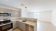 Located at 80 South Rd, Unit 401 in Farmington, CT, this thoughtfully designed two-bedroom, two-bathroom residence offers a clean, modern aesthetic throughout its well-appointed single-floor layout. The open-concept living and kitchen area serves as the heart of the home, featuring light wood plank flooring, recessed lighting, and a seamless flow between spaces. The kitchen is equipped with sleek gray cabinetry, quartz countertops, stainless steel appliances including a dishwasher, an undermount sink, and a stylish pendant light above the peninsula — ideal for both cooking and casual dining. Natural light fills the living area through a large window, creating a bright and welcoming atmosphere. A clean, well-lit hallway connects the main living space to the private quarters. Both bedrooms are carpeted and feature individual wall-mounted mini-split systems for personalized climate control. The spacious primary bedroom offers ample room and closet access, while the second bedroom features angled ceiling details and a window with natural light. Three closets throughout provide generous storage. Both bathrooms are finished with marble-style tile flooring, gray vanities, white quartz countertops, and large mirrors. One bathroom includes a walk-in shower, while the other features a combined layout — both delivering a refined, contemporary feel.