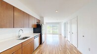 Located at 3030 S Water St in Pittsburgh's South Side neighborhood, this one-bedroom, one-bathroom unit offers a thoughtfully laid-out floor plan across a single level. The open living and kitchen area greets you upon entry, featuring warm-toned wood cabinetry that extends floor to ceiling, bright white countertops, and a full suite of stainless steel appliances including a range, built-in microwave, and dishwasher. Durable hardwood-style flooring runs throughout the main living and kitchen areas, adding warmth and easy maintenance to everyday living. A hallway connects the main living space to the private bedroom and bathroom, providing a clear and functional flow. The bedroom is comfortably sized, finished with soft carpeting and a window that frames views of lush greenery — offering a calm, natural backdrop. The bathroom continues the cohesive design aesthetic with large-format tile flooring, a wood-toned vanity, and a full tub and shower combination. Throughout the unit, crisp white walls and clean lines lend a modern, move-in-ready feel. The overall ambiance is bright, functional, and well-appointed, making this an ideal space in a convenient Pittsburgh location.