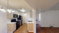 This single-floor unit offers a well-organized layout connecting the kitchen, living area, and bedrooms in a functional, open arrangement. The kitchen is designed in a galley style, featuring cream-toned cabinetry, white countertops, and a full suite of black appliances including a gas range, microwave, and dishwasher, complemented by a stainless steel refrigerator. A double-basin sink is positioned on a peninsula that separates the kitchen from the adjoining living area, and a pendant chandelier adds a decorative touch overhead.

The living area is generously proportioned, with wood-style flooring that extends throughout the unit, creating a cohesive and easy-to-maintain surface. A sliding glass door opens directly to a private balcony, bringing in natural light and providing outdoor access.

The two bedrooms are bright and well-sized, each featuring windows with vertical blinds that allow for adjustable natural light. One bedroom includes a ceiling fan with integrated lighting. Both bathrooms are similarly appointed, each offering a single-sink vanity with cabinetry beneath, a mirror, tub-shower combination with tiled surround, and wood-style flooring. One bathroom provides direct access to a dedicated closet for added storage convenience.