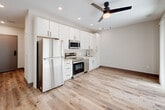 Located at 555 Boulevard NE in Atlanta's vibrant Old Fourth Ward neighborhood, this modern studio offers a thoughtfully designed single-floor layout. Light wood-tone luxury vinyl plank flooring flows throughout, complementing the crisp white walls and recessed lighting that keep the space feeling bright and contemporary.

The open-concept kitchen anchors the living area and is outfitted with full-size stainless steel appliances, including a refrigerator, electric range, over-the-range microwave, and dishwasher. White shaker-style cabinetry extends floor to ceiling, providing generous storage, while a subtle tile backsplash adds a refined finishing touch. A ceiling fan overhead serves both the kitchen and the open living area, which receives natural light through a sliding glass door that opens to an outdoor space.

A corridor leads to the full bathroom, which features a walk-in shower with white subway tile, a sleek vanity with white cabinetry and a solid countertop, matte black hardware, and marble-look tile flooring. A stacked washer and dryer unit is conveniently integrated into the bathroom, adding practical in-unit laundry. The overall design aesthetic is clean, modern, and functional, making this a well-appointed unit in the heart of Atlanta.