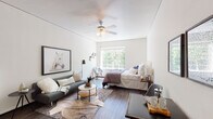 Located at 1417 SW 10th Ave in Portland, Oregon, this single-floor studio unit offers a well-organized and thoughtfully designed layout. The main living area serves as both a sleeping and lounge space, featuring dark hardwood-style flooring, a ceiling fan with light fixture, and a large window that invites abundant natural light and views of the surrounding greenery. The open layout comfortably accommodates a bed, seating area, and a small dining or work surface, creating a flexible and functional living environment. Crisp white walls throughout the space provide a clean, neutral backdrop that enhances the sense of openness. A private hallway connects the main room to additional areas, including a dedicated study nook complete with built-in shelving, a compact desk, and wall sconce lighting — ideal for focused work or reading. The bathroom features classic detailing with a warm-toned wood vanity, mosaic tile flooring, a pedestal-style sink, and a full tub and shower combination with tile surround. A wall-mounted medicine cabinet with mirror adds practical storage. The unit also includes in-unit appliances visible in the floorplan overview. The overall ambiance is modern yet understated, with a cohesive neutral palette and clean lines throughout.