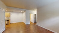 This efficiently designed single-floor residence offers three bedrooms and one bathroom across a thoughtfully arranged floor plan. Warm hardwood-style flooring runs consistently throughout the unit, creating a cohesive and inviting atmosphere.

The living room serves as the central gathering space, featuring a large window and a private entry door that welcomes abundant natural light and greenery views. The galley-style kitchen is well-appointed with light maple cabinetry, granite-look countertops, and stainless steel appliances including a range, dishwasher, and refrigerator, all illuminated by recessed ceiling lights.

The primary bedroom offers a comfortable footprint with access to a closet, while the additional bedrooms are bright and versatile — one notably featuring dual windows with outdoor views and a ceiling fan for added comfort. All bedrooms continue the hardwood-style flooring and maintain a clean, neutral palette.

The shared bathroom includes a single-sink vanity with tile-look countertops, a large mirror, wood cabinetry, and a shower-tub combo. Throughout the unit, white trim and neutral beige walls contribute to a clean, move-in-ready aesthetic. Textured ceilings and practical wall heating units complete the functional design of this well-organized residence.