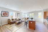 Located at 375 Gartrell St SE in Atlanta's vibrant Grant Park neighborhood, this 2-bedroom, 1-bathroom residence offers a thoughtfully designed open-concept layout with modern finishes throughout. Light-toned hardwood floors run continuously through the space, complementing the neutral color palette and recessed lighting.

The combined kitchen and living area forms the heart of the home. The kitchen features warm wood cabinetry extending to the ceiling for generous storage, granite countertops, black appliances, and a center island with bar seating — ideal for casual dining or entertaining. The open living area is bathed in natural light from multiple large windows that frame views of the Atlanta skyline and surrounding treetops.

A wide hallway connects the main living area to the private quarters, lending a clean, organized flow to the floor plan. The spacious primary bedroom accommodates a full suite of furniture and includes a ceiling fan and a window with tranquil outdoor views. The second bedroom mirrors the same bright, airy aesthetic. The full bathroom is finished with a granite-topped wood vanity, a tub-shower combination, and tile-look flooring, maintaining the cohesive design found throughout. The overall ambiance is modern, clean, and comfortable.