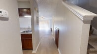 This two-story home offers a thoughtfully organized layout spread across two floors. The main level hosts the combined living, dining, and kitchen area, along with a laundry space and a hallway connecting the key areas. The living room is a standout space, anchored by a full brick fireplace flanked by built-in white shelving units on both sides — an inviting focal point that adds both character and storage. Light hardwood-style flooring runs throughout the main level, complemented by textured ceilings and a ceiling fan. A sliding glass door floods the living area with natural light. The galley-style kitchen features warm wood cabinetry, light countertops, black appliances including a range and refrigerator, and a sink with a window above. Upstairs, two carpeted bedrooms each include ceiling fans and window blinds that allow natural light. The spacious primary bedroom features a large window with outdoor views and a built-in shelf. Both bedrooms include closets with sliding doors. The two bathrooms are clean and functional, with one featuring a tiled shower-tub combination. The staircase connects both levels, completing this efficient and comfortable two-story home.