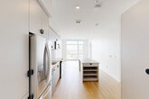 Located at 1520 Irving St in Denver's vibrant West Colfax neighborhood, this modern one-bedroom, one-bathroom residence offers a clean, contemporary design across a single thoughtfully laid-out floor. Light hardwood flooring flows throughout the main living areas, complementing the bright white walls and recessed lighting that give the space an open, airy feel.

The combined kitchen and living area forms the heart of the home. The kitchen is well-appointed with stainless steel appliances — including a French-door refrigerator, range, and over-the-range microwave — sleek white cabinetry, a penny-tile backsplash, and a undermount sink with a matte black faucet. A freestanding island with open shelving adds both storage and function. Large floor-to-ceiling windows at the end of the living area flood the space with natural light and offer sweeping views of the Denver cityscape and the mountains beyond.

The bedroom is a serene retreat with soft carpeting, clean white walls, and its own large window framing city views. It connects directly to the bathroom, which features a modern slate-blue floating vanity, a framed mirror, matte black hardware, and warm wood-tone flooring. A dedicated closet provides additional storage. This residence delivers a polished, modern aesthetic in a prime Denver location.