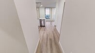 Located on the 8th floor in the heart of downtown Calgary, this one-bedroom, one-bathroom unit offers a clean, modern aesthetic throughout. Light-toned laminate hardwood flooring runs continuously across the open-concept living space, creating a cohesive and airy feel from entry to living room.

The kitchen is thoughtfully designed with crisp white cabinetry, white quartz countertops, a subway tile backsplash, and a full suite of stainless steel appliances including a refrigerator, electric range, over-the-range microwave, and dishwasher. Pendant lighting above the peninsula adds a contemporary touch while defining the kitchen from the adjoining living area.

The living room is bathed in natural light through floor-to-ceiling windows and a sliding glass door that opens directly onto a private balcony. The outdoor space overlooks the Calgary downtown skyline, offering an impressive urban backdrop.

The bedroom is comfortably sized, featuring large windows with vertical blinds, a built-in closet, and the same warm hardwood flooring. The bathroom is finished in a clean, minimalist style with white tile, a soaker tub and shower combination, a white vanity with quartz countertop, and brushed nickel fixtures throughout. The overall ambiance is bright, functional, and well-suited to modern urban living.