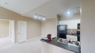 Located at 790 Emory Valley Rd in Oak Ridge, Tennessee, this single-floor residence offers a thoughtfully designed layout with a warm, neutral color palette throughout. The open-concept kitchen is a standout feature, equipped with crisp white cabinetry, dark granite countertops, black appliances including a refrigerator, electric range, and microwave, and a peninsula that doubles as a breakfast bar. Wood-look flooring runs through the kitchen, providing a clean, durable surface that complements the overall aesthetic. The living area is highlighted by dramatic vaulted ceilings and track lighting, creating an airy, spacious atmosphere. Plush wall-to-wall carpeting adds warmth and comfort underfoot. The bedroom features its own ceiling fan, generous closet space, and a large walk-in closet outfitted with wire shelving for ample storage. The bathrooms are finished with dark granite vanity tops, white cabinetry, and wood-look flooring, each including a full tub-shower combination with white tile surround. The consistent use of neutral tones, quality finishes, and practical design elements throughout the space creates a comfortable and functional living environment well-suited for everyday life.
