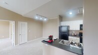 Located at 790 Emory Valley Rd in Oak Ridge, Tennessee, this single-floor residence offers a thoughtfully designed layout with a warm, neutral color palette throughout. The open-concept kitchen is a standout feature, equipped with crisp white cabinetry, dark granite countertops, black appliances including a refrigerator, electric range, and microwave, and a peninsula that doubles as a breakfast bar. Wood-look flooring runs through the kitchen, providing a clean, durable surface that complements the overall aesthetic. The living area is highlighted by dramatic vaulted ceilings and track lighting, creating an airy, spacious atmosphere. Plush wall-to-wall carpeting adds warmth and comfort underfoot. The bedroom features its own ceiling fan, generous closet space, and a large walk-in closet outfitted with wire shelving for ample storage. The bathrooms are finished with dark granite vanity tops, white cabinetry, and wood-look flooring, each including a full tub-shower combination with white tile surround. The consistent use of neutral tones, quality finishes, and practical design elements throughout the space creates a comfortable and functional living environment well-suited for everyday life.