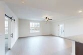 Located at 629 Old Liverpool Rd in Liverpool, NY, this well-designed 2-bedroom, 1-bathroom residence offers a thoughtful single-floor layout that maximizes comfort and functionality. The open-concept living and kitchen area serves as the heart of the home, featuring light wood-style flooring, crisp white walls, and a ceiling fan that enhances the bright, airy atmosphere. Natural light pours in through large windows, and a glass-paneled door provides access to an outdoor deck. The kitchen is outfitted with rich dark cabinetry, granite countertops, stainless steel appliances including an electric range and over-the-range microwave, and matching wood-style flooring that ties the space together seamlessly. Both bedrooms are carpeted for warmth and comfort, each featuring ceiling fans and windows with outdoor views. The spacious primary bedroom includes a generous walk-in closet with wire shelving systems offering ample storage. The full bathroom is clean and modern, featuring a combination tub and shower with sliding glass doors, light flooring, and accessibility-friendly grab bars. A dedicated laundry area with a full-size Whirlpool washer and dryer adds everyday convenience to this well-appointed residence.