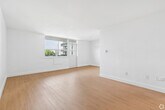 Located at 1577 Lawrence Avenue West in Toronto's Mount Dennis neighbourhood, this one-bedroom, one-bathroom unit offers a clean, functional layout across a single floor. The interior is finished with warm light hardwood flooring throughout and crisp white walls, creating a bright and airy atmosphere that maximizes the natural light flowing in from multiple windows.

The living room is generously proportioned, with large windows that frame views of the surrounding greenery and provide direct access to a private balcony. The balcony overlooks open parkland and tree canopy, offering a pleasant outdoor retreat with a notably open skyline perspective.

The bedroom is a comfortable size, featuring a large window that admits ample natural light and a built-in sliding-door closet, providing practical storage. The room's simple, clean design offers versatility for various furniture arrangements.

The bathroom is finished with white subway-style wall tiles surrounding a full soaker tub and shower combination, fitted with chrome fixtures for a timeless look.

Throughout the unit, the consistent use of light tones and hardwood-style flooring ties each space together cohesively. The overall ambiance is clean, understated, and move-in ready, well-suited for those seeking a practical and comfortable home in a green Toronto neighbourhood.