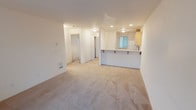 Located at 10124 9th Ave, Unit B308 in Everett, WA 98204, this single-floor residence is thoughtfully designed for comfortable everyday living. The open-concept living area is finished with neutral wall-to-wall carpeting and flows seamlessly into the kitchen, which is defined by a peninsula counter with bar seating — ideal for casual dining or entertaining. The kitchen is well-appointed with light wood cabinetry offering generous storage, a double-basin stainless steel sink, tile flooring, and white appliances including a range, microwave, and refrigerator.

The unit features multiple bedrooms, each carpeted and filled with natural light from large windows that frame outdoor greenery. One bedroom includes a spacious closet with bifold doors and a baseboard heater, while another offers a private, versatile layout. The primary bedroom includes a sliding glass door that opens to a private balcony.

Two full bathrooms serve the unit, each finished with light wood vanities, tile flooring, and bright vanity lighting. One bathroom includes a shower-tub combination, while the other features a glass-enclosed standing shower. Throughout the unit, the clean, neutral palette and consistent design elements create a bright and functional living environment.