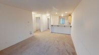 Located at 10124 9th Ave, Unit B308 in Everett, WA 98204, this single-floor residence is thoughtfully designed for comfortable everyday living. The open-concept living area is finished with neutral wall-to-wall carpeting and flows seamlessly into the kitchen, which is defined by a peninsula counter with bar seating — ideal for casual dining or entertaining. The kitchen is well-appointed with light wood cabinetry offering generous storage, a double-basin stainless steel sink, tile flooring, and white appliances including a range, microwave, and refrigerator.

The unit features multiple bedrooms, each carpeted and filled with natural light from large windows that frame outdoor greenery. One bedroom includes a spacious closet with bifold doors and a baseboard heater, while another offers a private, versatile layout. The primary bedroom includes a sliding glass door that opens to a private balcony.

Two full bathrooms serve the unit, each finished with light wood vanities, tile flooring, and bright vanity lighting. One bathroom includes a shower-tub combination, while the other features a glass-enclosed standing shower. Throughout the unit, the clean, neutral palette and consistent design elements create a bright and functional living environment.