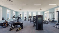Located at 12525 Oldehurst Place in Charlotte, NC, this fitness center is designed to support a full range of workout routines within a spacious, single-floor layout. The room is finished with soft teal-painted walls and patterned carpet flooring, creating an energetic yet comfortable exercise environment. Ceiling fans are evenly distributed throughout, complementing the overhead fluorescent lighting to maintain air circulation and visibility across the space.

Large white-framed windows line multiple walls, allowing abundant natural light to filter in and offering views of the surrounding community. The cardio section features True-brand treadmills, a StairMaster stepper, a rowing machine, and stationary bikes, while the strength training area is equipped with True cable and resistance machines, a functional training rack with TRX suspension straps, a dumbbell rack, and adjustable benches. A wall-mounted flat-screen display adds a multimedia element to the space.

The layout is thoughtfully arranged to provide ample room between equipment stations, supporting safe and efficient movement throughout. A glass-paneled interior door connects to an adjacent space, contributing to the overall accessibility and flow of the facility.