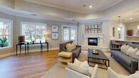 Located at 11321 Colbert Creek Loop in Raleigh, NC, this single-story community clubhouse is designed with an elegant and welcoming aesthetic throughout. The grand entrance lobby immediately impresses with soaring double-height ceilings, floor-to-ceiling sheer drapery, and an expansive wall of windows and French doors that flood the space with abundant natural light and provide views of the surrounding greenery. Light-toned tile flooring, neutral furnishings, and carefully curated décor create a refined yet comfortable atmosphere.

Adjacent to the lobby, a spacious lounge area features a coffered tray ceiling, a classic fireplace with decorative mantle, hardwood flooring, and ample seating arranged around a central wet bar with pendant lighting — ideal for socializing. A dedicated media lounge offers a sophisticated retreat with blue shiplap accent walls, a mounted flat-screen television, plush seating, and large windows overlooking the outdoors.

A bright dining area with hardwood floors and crisp white millwork provides an inviting setting for gatherings, while a private conference room with steel-blue walls, large windows, a round table, and framed artwork offers a focused meeting environment. Completing the space is a well-appointed coffee bar featuring granite countertops, white cabinetry, and a modern coffee station — a thoughtful amenity for daily convenience.