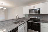 Located at 4260 Brownsboro Rd in Winston-Salem, NC, this single-floor unit offers a well-designed layout with a variety of functional living spaces. The updated kitchen is a standout feature, showcasing white shaker-style cabinetry, granite countertops, a subway tile backsplash, and a full suite of stainless steel appliances including a refrigerator, range, microwave, and dishwasher. Light wood-look flooring runs throughout the kitchen, adding warmth and a modern touch. The living and dining areas are carpeted and filled with natural light, courtesy of large sliding glass doors fitted with vertical blinds that open to an outdoor view. A dedicated dining space features an elegant chandelier overhead. The bedrooms are generously sized, each finished with soft carpeting and windows with blinds that allow natural light to filter in comfortably. The primary bedroom includes a walk-in closet and direct access to a bathroom. The bathroom presents a clean, updated aesthetic with white cabinetry, a white countertop vanity, and wood-look flooring that mirrors the kitchen. Throughout the unit, neutral tones and clean finishes create a cohesive and inviting atmosphere well-suited for comfortable everyday living.