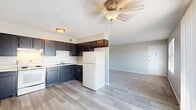 This single-floor unit offers a practical and functional layout designed for comfortable everyday living. The kitchen is outfitted with dark navy cabinetry — both upper and lower — paired with light countertops, a double stainless steel sink, a white electric range, and a full-size refrigerator. Wood-look vinyl plank flooring runs throughout the kitchen area, providing a clean and durable surface. The kitchen opens directly into the living area, which transitions to plush wall-to-wall carpeting and features a ceiling fan with light fixture overhead. Large windows and a sliding glass door bring in generous natural light and provide outdoor access, enhancing the sense of openness in the living space. The bedrooms are carpeted and finished with neutral-toned walls, each featuring individual windows that allow in natural light. The primary bedroom stands out with two sets of bifold closet doors, offering an abundance of storage space. Additional bedrooms are well-proportioned and versatile. The bathroom includes a vanity with dark cabinetry, a toilet, and a full tub and shower combination with tiled surround, finished with wood-look flooring. Throughout the unit, clean lines, neutral tones, and practical finishes create a cohesive and move-in-ready environment.