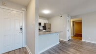 This single-floor residence offers a clean, modern aesthetic with a cohesive neutral color palette and wood-look luxury vinyl plank flooring throughout. The open-concept kitchen serves as a functional centerpiece, featuring white shaker-style cabinetry, a subway tile backsplash, quartz-look countertops, and a full suite of stainless steel appliances including a gas range, microwave, and refrigerator. A peninsula with an integrated sink provides additional prep space and casual dining potential.

The living areas are bright and open, with ceiling fans and windows fitted with vertical blinds that allow for natural light control. The layout flows comfortably between the main living zone and the adjacent rooms, all connected by consistent flooring and soft, neutral wall tones.

The bedrooms are well-sized, each offering ceiling fans and ample built-in closet storage — including a room with dual closets, providing generous organizational capacity. Recessed lighting and clean white trim add a polished finish.

The bathroom features full-surround marble-look porcelain tile, a soaking tub with brushed nickel fixtures, and a built-in wall niche for convenient storage. Overall, the space presents a fresh, move-in-ready interior with thoughtful finishes throughout.