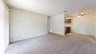 Located at 5808 E 71st St in Tulsa, Oklahoma, this two-bedroom, two-bathroom unit offers a well-organized single-floor layout designed for comfortable everyday living. The living room serves as the central gathering space, featuring plush wall-to-wall carpeting, a textured ceiling, and a distinctive horizontal shiplap-style accent wall. A sliding glass door with vertical blinds opens to a private balcony, bringing in natural light and outdoor views of the surrounding greenery. The kitchen is positioned adjacent to the living area and includes dark cabinetry, a countertop workspace, and essential appliances, making it both functional and accessible. The primary bedroom provides a comfortable retreat with carpeted flooring, a window with natural light, and access to a dedicated closet. The second bedroom is similarly appointed with soft carpeting, a textured ceiling, its own closet, and direct sightlines to the kitchen. Three closets throughout the unit offer generous storage. Both bathrooms feature tub-shower combinations — one with a tiled surround and the other with a solid enclosure — complemented by dark wood-tone cabinetry and wood-look flooring. The overall aesthetic is clean and neutral, providing a versatile canvas for personalization.