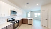 Located at 2700 E Howard Ln in Manor, TX, this well-designed 2-bedroom, 1-bathroom unit offers a clean, contemporary aesthetic throughout its single-floor layout. The open-concept kitchen and living area serves as the heart of the home, featuring a two-tone cabinet design with rich walnut-finish lower cabinets and crisp white upper cabinets, complemented by a white subway tile backsplash. Stainless steel appliances — including a refrigerator, electric range, over-the-range microwave, and dishwasher — add a polished, modern touch. A kitchen island with a built-in sink and pendant lighting overhead enhances both functionality and style. Light wood-style flooring flows seamlessly throughout the main living areas, reflecting natural light from multiple windows. A ceiling fan anchors the living room, which benefits from an open, airy feel. Both bedrooms are well-proportioned, with ceiling fans, natural light from windowed walls, and views of the surrounding area. The primary bedroom includes a built-in closet with shelving for organized storage. The bathroom features a full tub-shower combination with clean white tile surround. Recessed lighting and a neutral color palette throughout lend the space a bright, move-in-ready appeal.