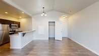 Located at 827 E Riverside Dr in Eagle, Idaho, this well-appointed single-floor residence offers a thoughtfully designed layout with a clean, modern aesthetic. The living area showcases striking vaulted ceilings fitted with a ceiling fan, wood-style flooring, and a sliding glass door that opens to a private balcony, flooding the space with natural light. An elegant chandelier highlights the dining area, which connects seamlessly to the kitchen via a breakfast bar. The kitchen is equipped with stainless steel appliances—including a refrigerator, range, and built-in microwave—dark cabinetry, granite-style countertops, and recessed lighting, making it both functional and stylish. The bedrooms feature plush carpeting and walk-in closets, providing ample storage. Large windows in each bedroom invite natural light and views of the surrounding landscape. The bathrooms are finished with dark vanity cabinetry, granite-style countertops, and slate-toned tile flooring. One bathroom includes a full tub-shower combination, while a second offers a standalone vanity setup. Throughout the residence, neutral tones and clean finishes create a cohesive and contemporary atmosphere ideal for comfortable everyday living in the heart of Eagle, Idaho.