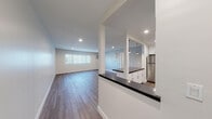 Located at 6455 Reseda Blvd in the Reseda neighborhood of Los Angeles, this single-floor unit offers a clean, modern aesthetic throughout. The open-concept layout connects the living area and kitchen seamlessly, with wood-look flooring running through the main living spaces and recessed lighting overhead.

The kitchen is a standout feature, outfitted with crisp white shaker cabinetry, dark countertops, and a full suite of stainless steel appliances including a gas range, microwave, and refrigerator. Pendant lights hang above the peninsula, which provides additional prep space and a natural divider between the kitchen and living area.

The living room is generously proportioned, with soft gray walls, recessed lighting, and a window dressed with vertical blinds that lets in natural light. Bedrooms feature plush carpeting, ample wall space, and windows with views of the surrounding area, along with wall-unit air conditioning for comfort.

The bathroom is finished in clean white tile, featuring a full soaking tub and shower combination with a window above for natural ventilation. A dark-topped vanity with white cabinetry complements the overall design. A well-organized walk-in closet with built-in shelving, drawers, and dual hanging rods provides excellent storage capacity throughout the unit.