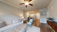 Located at 100 Pinckney Marsh Lane in Port Royal, South Carolina, this single-story residence offers a thoughtfully designed open-concept layout with consistent, contemporary finishes throughout. The living area serves as the heart of the home, featuring warm hardwood-style flooring, crown molding, recessed lighting, and a ceiling fan. Large windows allow generous natural light to fill the space, while the open sightlines connect seamlessly to the dining area and kitchen.

The kitchen is well-equipped with white shaker-style cabinetry, white subway tile backsplash, stainless steel appliances including a refrigerator, range, microwave, and dishwasher, and a deep undermount sink. Light hardwood-style flooring and recessed lighting contribute to a clean, functional aesthetic.

A hallway connects the main living areas to the bedrooms, each featuring plush carpet, ceiling fans, and windows that invite natural light. The bedrooms are served by well-appointed bathrooms boasting elongated white vanities with dual sinks, framed mirrors, wood-look flooring, and separate toilet areas with shower/tub combinations. Additional storage is provided by a spacious walk-in closet with wire shelving systems. Crown molding and neutral tones throughout lend the entire space a cohesive, refined character.