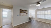 Located at 1820 S Brookstone Village Dr in Independence, Missouri, this single-floor residence offers a thoughtfully designed layout with a clean, modern aesthetic. The open-concept living and dining area is anchored by warm hardwood-style flooring and neutral walls, creating a bright and welcoming atmosphere. A ceiling fan adds comfort to the living space, while a peninsula bar with stools provides a casual seating option that flows seamlessly into the dining nook. The dining area is bathed in natural light from multiple windows fitted with white horizontal blinds, and is accented by a stylish pendant light fixture overhead. The kitchen is well-appointed with stainless steel appliances, including a refrigerator, dishwasher, electric range, and over-the-range microwave, all complemented by crisp white cabinetry and light marble-style countertops. Light wood-tone flooring and a window above the sink keep the kitchen feeling airy and functional. An in-unit laundry area is conveniently accessible from the kitchen. The bedroom features plush carpeting, soft gray walls, a generous closet, and a bright window that fills the room with natural light. The bathroom offers a full tub-shower combination with chrome fixtures, a curtain rod, and a mirrored vanity, finished with wood-style flooring for a cohesive look throughout the home.