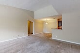 This single-floor residence offers a functional and well-organized layout designed for comfortable everyday living. The living area greets occupants with vaulted ceilings that lend a sense of spaciousness, neutral beige walls, and plush wall-to-wall carpeting. A ceiling fan with a light fixture provides ventilation, while a front-facing window allows natural light to fill the room. The front entry transitions from wood-style flooring to carpet seamlessly.

The kitchen is accessed via an open peninsula counter, creating a natural division between the living and dining spaces. Dark espresso-toned cabinetry lines the kitchen walls, complemented by stone-look countertops, a stainless steel double sink, and black appliances including a refrigerator, range, and dishwasher. Track lighting overhead enhances the functional workspace, and wood-style flooring runs throughout the kitchen.

The bedrooms are carpeted and generously proportioned, with one room featuring a walk-in closet equipped with a wire shelving system. The bathrooms include dark-framed vanity mirrors, espresso cabinetry, stone-look countertops, and wood-style flooring, with one bathroom featuring a full soaking tub and shower combination. The overall palette is warm and neutral throughout.
