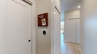 This well-designed single-floor residence offers a cohesive blend of modern aesthetics and functional living spaces. The interior is unified by light hardwood flooring that extends through the main living areas, complemented by neutral-toned walls that create a bright, welcoming atmosphere throughout.

The hallway entrance sets a clean, contemporary tone, featuring sliding barn-style doors, recessed lighting, and a smart thermostat for convenient climate control. It leads seamlessly into the open-concept kitchen and living area. The kitchen is a standout space, showcasing a two-toned cabinet design combining crisp white upper cabinetry with warm wood-finish lower cabinets. A central island with seating, light stone countertops, subway tile backsplash, stainless steel appliances, and pendant lighting complete this well-appointed space.

The living area is bright and airy, anchored by a large sliding glass door that opens to a private balcony overlooking a natural outdoor setting, allowing abundant natural light to fill the room. The bedrooms offer plush carpeting, large windows with outdoor views, and a calm, restful ambiance. A full bathroom features wood-toned cabinetry and clean, minimalist finishes, while a half bath provides added convenience. Overall, the space presents a polished, modern living environment.