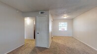 This single-floor unit is thoughtfully laid out to maximize functionality across its living spaces. The main living area features neutral-toned carpet, textured ceilings, and a central six-panel door that separates key zones within the unit. A window along the far wall allows natural light to filter in, creating a bright and open atmosphere. HVAC vents are positioned in the ceiling, ensuring efficient climate control throughout.

The kitchen is equipped with stainless steel appliances, including a refrigerator, electric range, microwave, and dishwasher. White cabinetry provides ample storage, while wood-look vinyl flooring adds a clean, modern contrast to the surrounding carpeted areas.

The bedrooms are carpeted and well-proportioned, each featuring windows with blinds that bring in natural light and outdoor views of surrounding greenery. One bedroom includes a ceiling fan with integrated lighting. The spaces offer a calm, neutral palette suitable for a variety of furnishing styles.

The bathroom is finished with wood-look vinyl flooring, a white tiled tub and shower combination with brushed nickel fixtures, and a standard toilet, providing a clean and practical design. Overall, the unit presents a functional and move-in-ready layout with consistent finishes throughout.