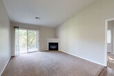 This well-designed two-bedroom, two-bathroom residence in Council Bluffs, Iowa offers a comfortable and functional single-floor layout. The living room serves as a central gathering space, highlighted by vaulted ceilings that lend an open, airy feel, plush carpeting, and a sleek fireplace with a white mantle. A sliding glass door connects the living area to an outdoor balcony, allowing natural light to fill the room. The kitchen features white cabinetry, white appliances including a refrigerator, electric range, and over-the-range microwave, all complemented by durable wood-look flooring that carries through the space. Both bedrooms are carpeted and offer generous proportions, with the primary bedroom boasting a walk-in closet equipped with wire shelving and a ceiling fan. The second bedroom includes a closet and benefits from natural light. The two bathrooms are finished with wood-look flooring, white vanity cabinetry, and tub/shower combinations. Clean neutral tones throughout the home create a cohesive, move-in-ready aesthetic that is both practical and inviting.