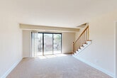 Located at 744 Fairview Ave in Takoma Park, Maryland, this two-bedroom, two-bathroom multi-level home offers a thoughtfully organized layout spread across two floors. The main level features a spacious living room filled with natural light, anchored by large sliding glass doors that open to a balcony overlooking the surrounding neighborhood. Neutral-toned carpet and clean white walls create a bright, open ambiance throughout. Adjacent to the living area, the dining space connects seamlessly to a galley-style kitchen equipped with light wood cabinetry, dark countertops, and black appliances including a full-size refrigerator and gas range. A convenient in-unit laundry area with a stacked washer and dryer is tucked nearby. A wood-railed staircase leads to the upper floor, where both bedrooms are situated. The generously sized primary bedroom features a wide picture window offering outdoor views and plush carpeting underfoot. A second bedroom provides comfortable accommodations with easy hallway access. The primary bedroom is served by a full bathroom with a tub/shower combination, vanity with storage, and tile flooring. Two closets offer additional storage throughout the home, completing this well-appointed Takoma Park residence.