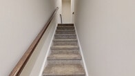 Located at 83 Terrace Green Dr in Barboursville, VA, this three-story home offers a thoughtfully designed layout across its floors. The entry-level garage features drywall construction with interior access doors, while the main living floor serves as the heart of the home. Here, the open-concept kitchen, dining, and living areas flow seamlessly together. The kitchen is a standout, featuring dark espresso cabinetry, a large center island with a white quartz countertop and undermount sink, stainless steel appliances, subway tile backsplash, and stylish pendant lighting — all complemented by light hardwood-style flooring. Bathrooms are finished with wood-look LVP flooring, navy vanities, and natural light from windows with lush outdoor views. The upper floor houses the four bedrooms, including a generously sized primary suite. Bedrooms feature plush carpeting and double-door closets. The home also includes nine closets throughout, a dedicated laundry room, utility room, and a bonus room, ensuring ample storage and flexibility. Carpeted staircases with wood handrails connect all three levels with ease, contributing to the home's clean, modern aesthetic and neutral color palette.