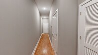 This single-floor, 4-bedroom, 2-bathroom home offers a thoughtfully designed layout that maximizes functionality and comfort. Warm hardwood-style flooring flows consistently throughout the space, complemented by neutral gray walls and crisp white trim that create a clean, cohesive aesthetic.

The kitchen is a standout feature, equipped with a full suite of stainless steel appliances — including a refrigerator, range, microwave, and dishwasher — set against sleek gray countertops and white shaker-style cabinetry. Recessed lighting illuminates the space effectively, and the layout opens conveniently toward the hallway connecting the rest of the home.

A central hallway with recessed ceiling lights provides smooth access to all four bedrooms, two bathrooms, and a dedicated closet. The primary bedroom is a comfortable size and includes ceiling fan fixtures found throughout the bedrooms. The walk-in closet features built-in shelving and hanging rods on multiple walls, offering ample organized storage.

Both bathrooms are finished with marble-style tile flooring. One bathroom features a tub-shower combination with white tile surround accented by a blue mosaic tile border. The second bathroom includes a gray vanity with a white countertop and a large mirror. Together, these spaces provide a polished, move-in-ready finish throughout the home.