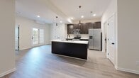 Located at 318 Meadowgreen Dr in Clarksville, Tennessee, this single-story home combines modern finishes with a functional, open layout. The kitchen serves as a central hub, featuring dark espresso cabinetry, stainless steel appliances including a refrigerator with ice maker, electric range, and microwave, all complemented by light quartz countertops. A substantial kitchen island with a built-in sink anchors the space, while pendant lighting and recessed fixtures illuminate the area. French doors provide natural light and connect the kitchen and living area to the outdoors.

The living area is finished with light wood-look flooring and a ceiling fan, creating a comfortable, airy atmosphere. Bedrooms are carpeted and include ceiling fans and windows that allow natural light and outdoor views. The primary bathroom offers a dual-sink vanity with dark cabinetry, a soaking tub with tile surround, and a separate shower. A secondary bathroom provides a tub-shower combo and single vanity. A dedicated laundry room houses stacked washer and dryer units with wire shelving, while a spacious walk-in closet features multi-level wire shelving and carpet flooring throughout.