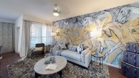 This single-floor residence showcases a well-planned layout that balances open communal areas with private retreats. The kitchen features white cabinetry, granite countertops, a white subway tile backsplash, and stainless steel appliances, offering a clean and functional workspace. Dark hardwood-style flooring runs through the kitchen and bathrooms, while plush carpet adds warmth to the bedrooms.

The living area serves as a striking focal point, anchored by a large-scale equestrian mural that spans an entire wall, creating a bold artistic statement. Adjacent to it, the dining space benefits from generous natural light through large windows dressed with patterned curtains.

Each bedroom is distinctly styled. One features deep navy accent walls paired with a triptych of teal artwork and large windows with outdoor views. Another presents a rich forest-green accent wall with a serene landscape painting above the bed. A third bedroom connects directly to a full bathroom with a soaking tub and gray subway tile surround.

The bathrooms are finished with gray subway tile, white cabinetry, granite countertops, and dark hardwood-style flooring, maintaining a cohesive design language. Ceiling fans are present throughout, and ample natural light flows into each room via large windows.