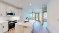 Located at 2000 Aspen Way in Franklin, Tennessee, this thoughtfully designed one-bedroom, one-bathroom residence offers a clean, modern aesthetic throughout. Light wood-tone flooring flows seamlessly across the entire unit, creating a warm and cohesive feel in every room.

The open-concept kitchen and living area serves as the heart of the home. The kitchen is outfitted with crisp white shaker cabinetry, white quartz countertops, stainless steel appliances including a side-by-side refrigerator with ice maker, a built-in microwave, and a sleek range. A central island with an undermount sink and matte black fixtures provides additional prep space and casual seating.

The living area is bright and airy, benefiting from a ceiling fan and a glass door that opens to a private balcony with views of the surrounding community. The bedroom is a comfortable retreat featuring a ceiling fan, natural light from large windows with blinds, and direct access to a spacious walk-in closet equipped with built-in shelving and hanging rods.

The bathroom features a white dual-sink vanity with ample cabinetry, matte black hardware, and framed mirrors with overhead lighting. Throughout the residence, modern panel doors with matte black hardware reinforce the contemporary design language, creating a polished and move-in-ready living space.