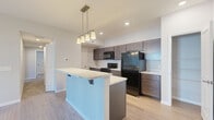 Located at 5500 Hildebrand Rd. in Columbus, Ohio, this single-floor residence offers a thoughtfully designed 2-bedroom, 2-bathroom layout that maximizes functionality and comfort. The kitchen serves as a central highlight, featuring rich dark cabinetry, marble-look countertops, a breakfast bar island with pendant lighting overhead, and black appliances including a range and refrigerator. Light wood-look flooring runs throughout the kitchen and main living areas, lending a clean, contemporary feel. A walk-in pantry provides generous storage directly off the kitchen. The two bedrooms are carpeted and bathed in natural light from large windows. The primary bedroom is notably spacious and includes dual closets for ample storage. The second bedroom is well-sized with its own window and plush carpet. Both bathrooms feature dark wood vanities, marble-look countertops, and light wood-look flooring. One bathroom includes a glass-enclosed walk-in shower, while the other offers a clean, accessible design with a single vanity and mirror. Neutral gray tones on the walls throughout create a cohesive, modern aesthetic. A hallway connects the rooms efficiently, completing this practical and attractively finished residence.