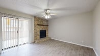 This well-appointed 1-bedroom, 1-bathroom unit offers a thoughtfully designed single-floor layout that maximizes functionality and comfort. The combined living room and kitchen area serves as the heart of the space, where a striking floor-to-ceiling stone fireplace with a wood mantle commands attention as a focal point. Light wood-style flooring runs throughout the main living areas, complemented by neutral-toned walls and a textured ceiling. A ceiling fan with integrated lighting adds both style and practicality. Vertical blinds cover a sliding glass door, allowing for natural light while providing privacy. The galley-style kitchen features warm wood cabinetry, light countertops, black appliances including a refrigerator and range, and a window that brings in additional natural light. A hallway leads to the private bedroom, which is finished with plush carpeting, a ceiling fan, and a window with blinds. The bedroom provides access to a spacious walk-in closet outfitted with dual hanging rods and shelving on both sides, offering generous storage capacity. The full bathroom includes a wood-vanity with a light stone-style countertop, a mirror, and a tiled tub-shower combination with wood-look flooring completing the space.