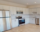 This contemporary 790 square foot apartment in Victoria, MN offers a thoughtfully designed living space. The heart of the home is the open-concept kitchen and living area, featuring crisp white cabinetry, stainless steel appliances, and a subway tile backsplash. The kitchen's L-shaped layout maximizes efficiency while maintaining an airy feel.

Natural light floods the living spaces through large windows, which also provide scenic views of the surrounding area. The primary bedroom, measuring 140 square feet, offers ample space and includes a closet with built-in organization systems. The second bedroom, while smaller, is versatile and could serve as a guest room or home office.

The bathroom showcases a modern vanity with a white countertop and a shower/tub combination. Throughout the apartment, neutral tones dominate, with light wood-look flooring in the main living areas and plush carpeting in the bedrooms. Recessed lighting and ceiling fans add both functionality and style.

The apartment's layout is efficient, with a hallway connecting the various rooms. The overall design emphasizes clean lines and a minimalist aesthetic, creating a blank canvas for personalization while maintaining a fresh, contemporary feel.