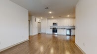 This well-appointed single-floor residence offers a thoughtfully designed layout that balances open living spaces with comfortable private areas. The open-concept living and kitchen area is anchored by warm hardwood-style flooring that flows seamlessly throughout the main living zone, complemented by recessed lighting and a ceiling fan that add both function and style.

The kitchen is a standout feature, boasting an abundance of white shaker-style cabinetry extending from floor to ceiling, granite-look countertops, and a full suite of stainless steel appliances including a range, over-the-range microwave, and dishwasher. The generous counter space and storage make this kitchen as practical as it is attractive.

The living area is bright and welcoming, with a large window allowing natural light to pour in, and a ceiling fan overhead. The bedroom features plush wall-to-wall carpeting, a ceiling fan, and a sizable window with exterior views, creating a calm and restful retreat.

The bathroom is finished in a crisp, all-white palette with white shaker vanity cabinets, marble-look countertops, built-in open shelving, a large mirror, and a tiled tub-shower combination — all set on hardwood-style flooring for a clean, cohesive look throughout.