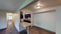 Located at 3804 Pine Terrace Blvd in Kalamazoo, Michigan, this single-floor unit offers a well-organized layout designed for comfortable everyday living. The open-concept living and dining area features durable wood-style flooring and is anchored by a sliding glass door that fills the space with natural light while providing direct access to an outdoor patio overlooking greenery. A pass-through breakfast bar connects the living area to the kitchen, creating a functional and social flow between spaces.

The kitchen is efficiently designed with dark espresso cabinetry extending to the ceiling, offering generous storage. Stainless steel appliances—including a refrigerator, range, over-the-range microwave, and dishwasher—provide modern functionality alongside light-toned countertops. Wood-style flooring continues throughout the kitchen, complementing the cabinetry.

The bedrooms are carpeted for comfort and each feature windows with blinds that invite natural light and outdoor views of surrounding trees. The rooms provide a quiet, neutral atmosphere with ample wall space. The bathroom includes a full tub-and-shower combination with tile surround, wood-style flooring, a vanity with dark cabinetry, and a mirror. The unit also appears to include an in-unit laundry area, adding everyday convenience to this practical Kalamazoo residence.
