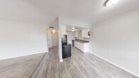 This well-organized one-bedroom, one-bathroom unit is thoughtfully laid out across a single floor, making efficient use of its compact footprint. The open-concept living and dining area greets you upon entry, featuring durable wood-look laminate flooring and neutral white walls that create a bright, clean atmosphere. A half-wall partition defines the transition into the kitchen without fully closing off the space, maintaining an airy, connected feel throughout the common areas.

The galley-style kitchen is equipped with black appliances, including an electric range, refrigerator, and dishwasher. White cabinetry lines both walls, providing ample storage, while brown laminate countertops offer generous prep space. The same laminate flooring continues seamlessly through the kitchen.

The bedroom is a comfortable, well-proportioned room featuring plush carpeting, a window that allows in natural light, and access to multiple closets, providing generous storage solutions. The overall layout also includes a dedicated hallway connecting the main living areas to the private spaces.

The bathroom is straightforward and functional, featuring a full-size tub and shower combination, a toilet, and overhead cabinetry for additional storage, with wood-look flooring completing the space. Throughout the unit, a consistent neutral color palette and clean finishes create a cohesive, move-in-ready environment.