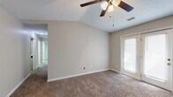 This single-story home offers a well-organized layout across two bedrooms, two bathrooms, a kitchen, dining room, dedicated laundry area, and a connecting hallway. Neutral warm-gray walls and white trim are consistent throughout, creating a cohesive and understated aesthetic.

The living and dining areas feature vaulted ceilings with ceiling fans, enhancing the sense of openness. French doors in one room allow natural light to filter in, while additional windows with blinds provide ventilation and brightness. Carpet flooring is found in the main living and bedroom areas, while wood-look vinyl or tile flooring runs through the kitchen, laundry, and dining spaces.

The primary bedroom is generously sized, featuring vaulted ceilings, a ceiling fan, a window for natural light, and direct access to a walk-in closet area. The second bedroom includes a skylight, adding a distinctive architectural detail and supplemental natural light.

The kitchen is equipped with white cabinetry, light-toned countertops, a double stainless steel sink, and ample upper and lower storage. The bathrooms feature white vanities with integrated sinks, wall mirrors, and standard fixtures. The laundry area includes washer and dryer hookups with wood-look tile flooring, offering a practical and self-contained utility space.