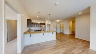 Located at 61 Grove Cir in Lillington, NC, this well-appointed single-story home offers three bedrooms, three bathrooms, and a thoughtfully designed open-concept floor plan. The combined kitchen and living area serves as the heart of the home, showcasing rich dark-espresso cabinetry, granite countertops, and a full suite of stainless steel appliances including a refrigerator, range, and microwave. A peninsula with bar seating and pendant lighting adds both functionality and style, while recessed lighting and light wood-style flooring create a bright, cohesive atmosphere throughout the main living space. A dedicated pantry with built-in shelving provides ample storage directly off the kitchen. The living area benefits from a ceiling fan and exterior door with sidelights, allowing natural light to filter in. Bedrooms are carpeted for comfort, with the primary bedroom offering direct access to its own en-suite bathroom featuring a double-sink vanity with granite countertops and dark cabinetry. Additional bathrooms echo the same refined finishes. The home also includes a convenient in-unit laundry area and two closets for added storage. Clean white walls, panel doors, and consistent finishes throughout give this home a polished, move-in-ready appeal.