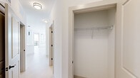 Located at 19 Harnett St in Wilmington, NC, this thoughtfully designed one-bedroom, two-bathroom residence offers a clean, modern aesthetic with a bright and airy atmosphere throughout. The open-concept kitchen and living area serves as the heart of the home, anchored by a sleek island with an undermount sink and light quartz countertops. The kitchen is outfitted with white shaker cabinetry, matte black hardware, stainless steel appliances, subway tile backsplash, and stylish pendant lighting — all set atop light-toned hardwood flooring that flows seamlessly through the main living spaces. Large windows flood the area with natural light and offer views of the surrounding Wilmington cityscape, while a door provides access to an outdoor balcony. The spacious bedroom features plush carpeting, a ceiling fan, and generous windows that continue the home's bright character. A well-appointed walk-in closet with wire shelving provides ample storage. The primary bathroom impresses with a dual-sink vanity, white cabinetry with matte black fixtures, a large mirror, and a glass-enclosed walk-in shower. A dedicated hallway closet adds further storage convenience. Clean white walls, recessed lighting, and consistent modern finishes create a cohesive, polished living environment throughout.